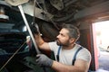 Auto repair shop worker checking client motor vehicle