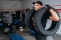 Auto repairman holds two tires, repairing service