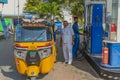 Auto rickshaw at a patrol station with the driver and gas station attendant in Puttaparthi