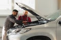 Auto service, repair, maintenance and people concept - mechanic men with wrench repairing car engine at workshop Royalty Free Stock Photo