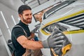 Auto service staff in uniform cleaning car with microfiber cloth. Car detailing and valeting concepts Royalty Free Stock Photo