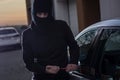 Auto thief in black balaclava trying to break into car Royalty Free Stock Photo