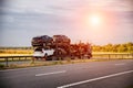 An auto transporter semi-trailer truck transports broken damaged cars from Europe in the summer against a sunset Royalty Free Stock Photo