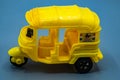toy motor. auto. autoriksha. tricycle taxi. tuk tuk, yellow auto on a gray background.