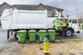 Automated Garbage Truck Picking Up Trash Container on Curb Royalty Free Stock Photo