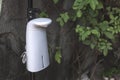 An automated hand sanitizer on a tripod installed at a garden area, possibly in an al fresco restaurant or swimming resort