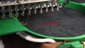 An automated machine embroiders pattern with red threads on a black cloth. Robotics works in tailoring production line