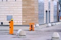 Automatic barrier of orange color with a white stripe and red warning stripes, for the entry of cars. Entrance to the courtyard of