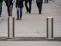 Automatic cylindrical barriers on the pedestrian zone against the background of blurry feet of pedestrians