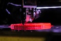 Automatic 3D printer machine printing red flat plastic model: close up