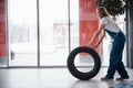 Automatic doors is in the front. Woman walks with brand new wheel to the car. Conception of repair Royalty Free Stock Photo