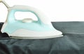 automatic electric iron pressing black slacks on ironing board