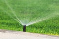 Automatic garden lawn sprinkler in action watering green grass Royalty Free Stock Photo