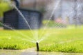 Automatic garden sprinkler in a public park. Gardening equipment. Watering the grass on lawn on a sunny summer day