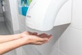 Automatic hand dryer in public toilet or restroom hygiene concept. A man hands using utomatic hand dryer in bathroom Royalty Free Stock Photo