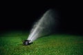 Automatic lawn sprinkler spraying water over golf course green grass Royalty Free Stock Photo