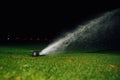 Automatic lawn sprinkler spraying water over golf course green grass Royalty Free Stock Photo