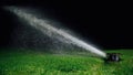 Automatic lawn sprinkler spraying water over golf course green grass Royalty Free Stock Photo