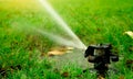 Automatic lawn sprinkler watering green grass. Garden, yard irrigation system watering lawn. Water saving or conservation from Royalty Free Stock Photo