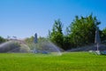 Automatic lawn sprinkler watering lawn with sunbeds. Garden irrigation system in action Royalty Free Stock Photo