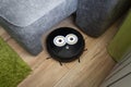 Automatic robot vacuum cleaner in black on wooden floor. New modern technologies for apartment cleaning. smart home electronic