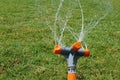 Automatic sprinkler system watering the lawn on a background of green grass, close-up Royalty Free Stock Photo