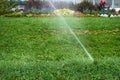 Automatic sprinkler system watering the lawn on a background of green grass, close-up Royalty Free Stock Photo