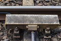 Automatic train braking system mounted on railway tracks, visible concrete sleepers and large stones between them.