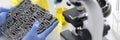 Automatic transmission lies in rubber gloves on table with microscope and test tubes in chemical laboratory closeup