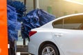 Automatic wash blue brush in action, white car comes out ready clean