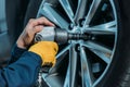 Cropped shot of automechanic unscrewing tire bolts on a lifted up car at a