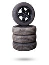 Automobile composition made up stack of tires and wheel with shiny black disc in the foreground against the background of cars in Royalty Free Stock Photo