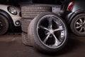 Automobile composition made up stack of tires and wheel with shiny metal disc in the foreground against the background of cars in Royalty Free Stock Photo