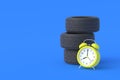 Automobile tires near alarm clock. Lifetime and warranty service of auto parts