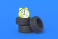 Automobile tires near alarm clock. Lifetime and warranty service of auto parts