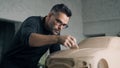Automotive designer drags across a wooden sculpting tool to carve design details