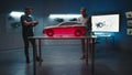 Automotive engineers examine the prototype car model in different shade of light