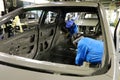 Two female auto workers working on the body work of an unpainted vehicle.