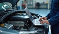 Automotive technician inspects car engine using laptop. Mechanic performs diagnostic check, seeking repair solution. Pro Royalty Free Stock Photo