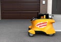 Autonomous delivery robot car in front of the garage with copy space on the left