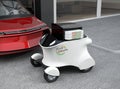 Autonomous delivery robot in front of the garage waiting for picking pizza