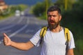 Autostop travel. Adventure and tourism concept. Man in casual wear waving down car, hitchhiking on roadside. Traveling