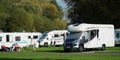 Autotrail camper van and others on campsite with campers relaxing.