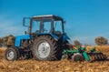 Autumn afternoon tractor rides and pulls the plow, plow a field after harvest of cereals - corn.