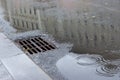 Autumn asphalt, metal grating stormwater on a city street. Autumn rainy weather with puddles, outflow of water from the highway. Royalty Free Stock Photo