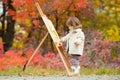 Autumn Baby Girl Drawing in Fall Leaves Park, Little Kid Painting, Children Creativity. Royalty Free Stock Photo