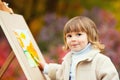 Autumn Baby Girl Drawing in Fall Leaves Park, Little Kid Painting, Children Creativity. Royalty Free Stock Photo