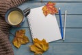 Composition with autumn leaves, blank notebooks, a cup of coffee on a blue wooden table