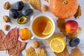 Autumn background of dry leaves with cup of tea, a small beautiful pumpkin, lemon, ripe plums and nectarines, walnuts