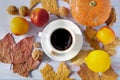 Autumn background of dry leaves with a white porcelain cup of coffee, pumpkin, lemon, ripe nectarines and walnuts